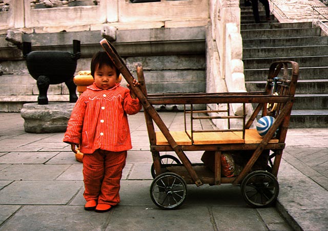 Girl in red standing next to her carriage mad of wood