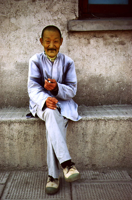 Chinese man in blue clothes smoking a cigarette
