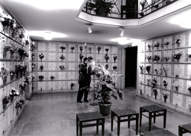 Woman lights a candle inside columbarium