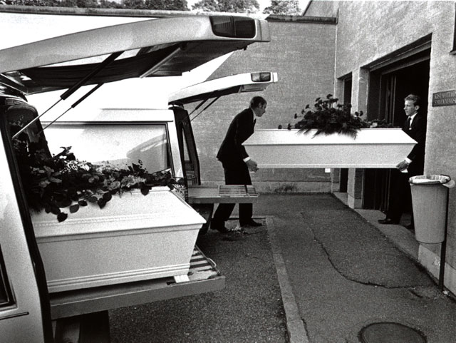 Coffin with flowers is carried to the crematorium, two hearses