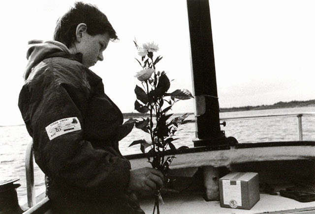 Boy with a rose next to the ashes inside a boat