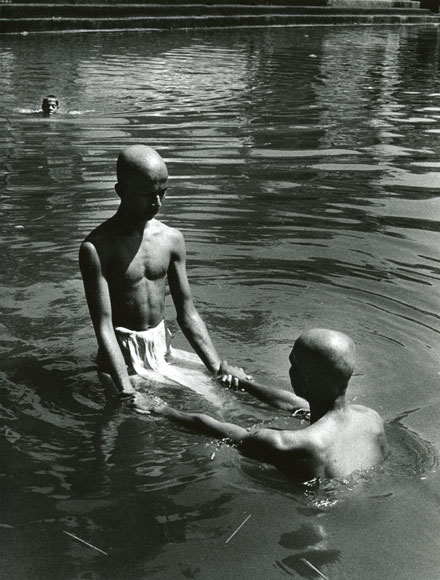 Two men with bald shaved heads holding hands performing holy ceremony puja in Kutithirta the holy pool in Gokarna India