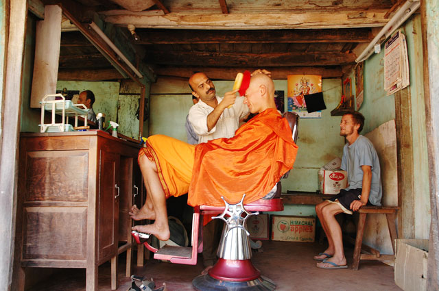 Barber shop, shaved bald man with bright red cloth. Westerner having a haircut