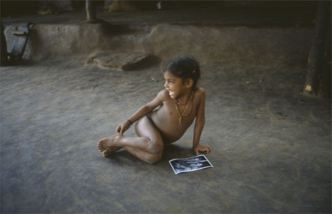 peasant girl sees her photo for the first time, sitting on the floor laughing