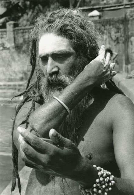 Sadhu combing his hair looking in the mirror long hair and long beard by Kutithirta the holy pool in Gokarna