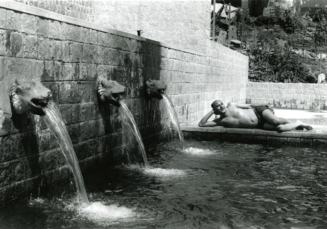 man by pool and fountain looking sexy and seductive smile