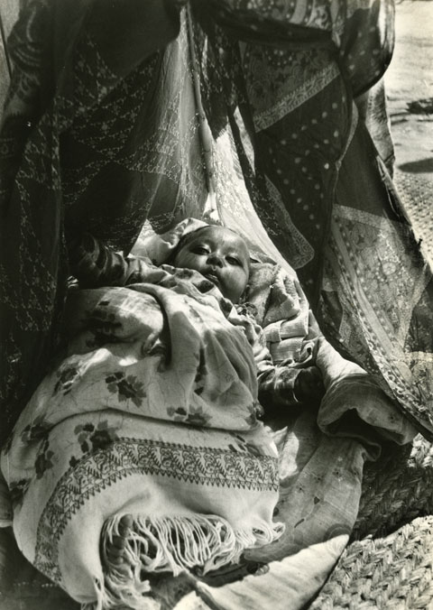 baby child with make up in the eyes resting in cosy tent Kathmandu Nepal