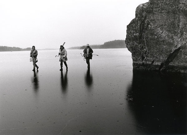 ice fishing three men walking on black ice with ice drills