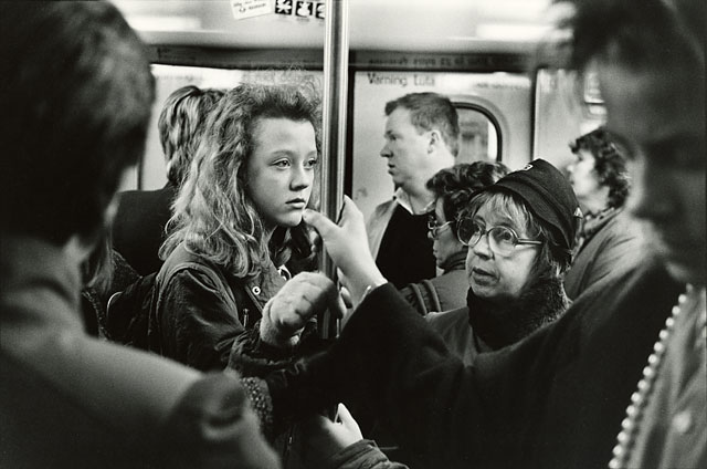 Stockholm subway, several people holding the metal bar and bored looks in their faces