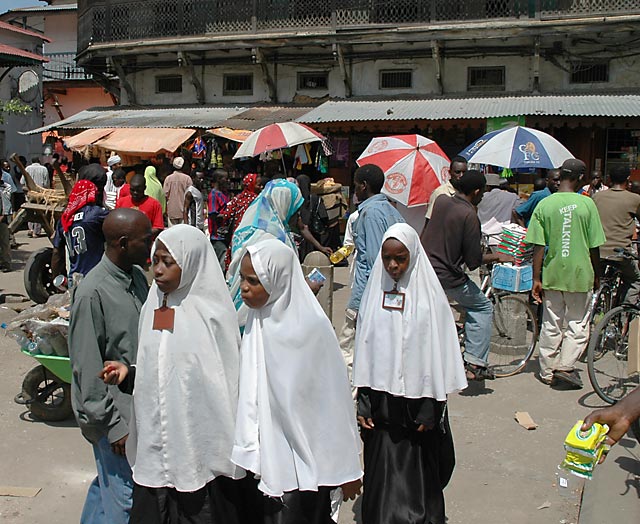 Three girls in white veils three umbrellas at the spice market Stone Town Zanzibar