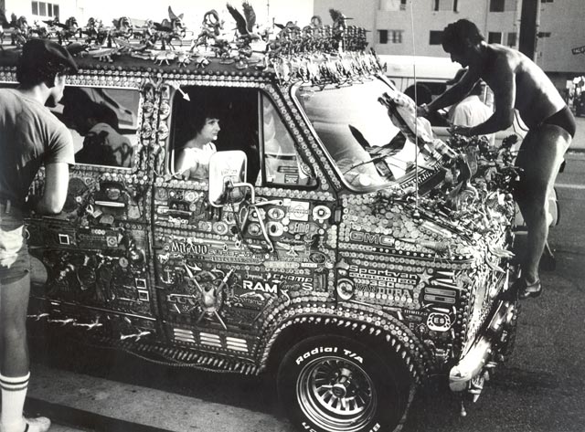 decorated van with ornaments mostly of brass. Owner cleaning the window