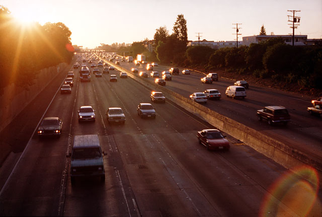 Los Angeles freeways, five lanes in each direction. Late afternoon with sun in the background